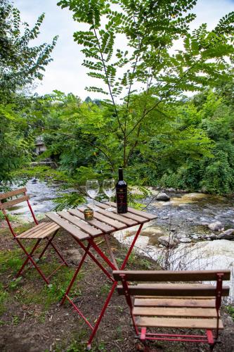 a picnic table with a bottle of wine and a bench at ADORA River Retreat in Avrig