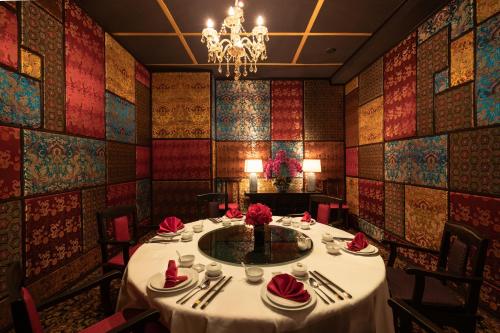 a dining room with a table and a chandelier at Royal Phuket City Hotel in Phuket Town