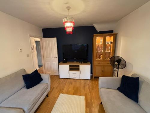 a living room with two couches and a flat screen tv at Cosy Shared Flat - Self Check-In, Free Street Parking in Leavesden Green