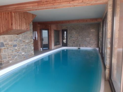 une grande piscine dans une maison avec un mur de briques dans l'établissement Chalet des Jonquilles - Magnifique maison avec piscine, aux Angles