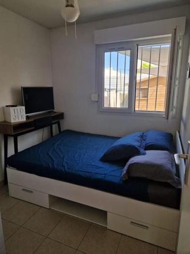 une chambre avec un lit avec des draps bleus et une fenêtre dans l'établissement Appartement avec Piscine, à Marseillan