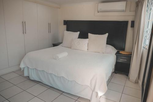 a bedroom with a large bed with white sheets and pillows at Beside Still Waters Boutique Hotel in Durban