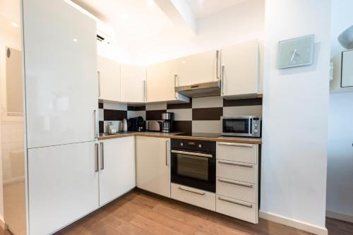 une cuisine avec des armoires et des appareils blancs dans l'établissement Cannes 1-Br Apartment in the Carré d’Or, à Cannes