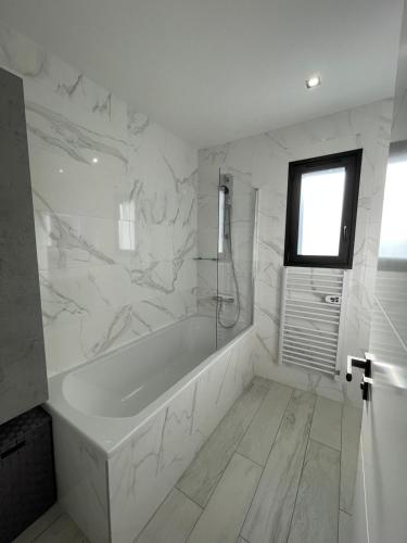 La salle de bains blanche est pourvue d'une baignoire et d'une fenêtre. dans l'établissement Villa Jérémy, à Sanary-sur-Mer