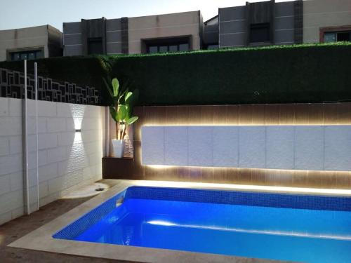 a blue swimming pool in front of a building at Villa haut standing avec piscine chauffée sans vis-à-vis et hammam in Ouled Moussa