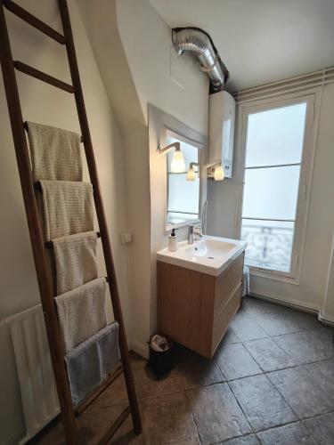 La salle de bains est pourvue d'un lavabo, d'un miroir et d'une échelle. dans l'établissement Summer price Beau 3 pièces près de Montmartre 1, à Paris