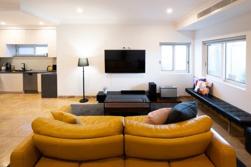 a living room with a yellow leather couch at Spacious Luxury Home Near Sydney Airport, CBD & Beaches in Sydney