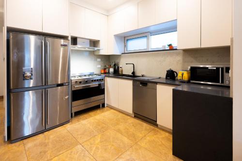 a kitchen with a stainless steel refrigerator and appliances at Spacious Luxury Home Near Sydney Airport, CBD & Beaches in Sydney