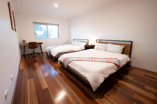 two beds in a room with wooden floors at Spacious Luxury Home Near Sydney Airport, CBD & Beaches in Sydney