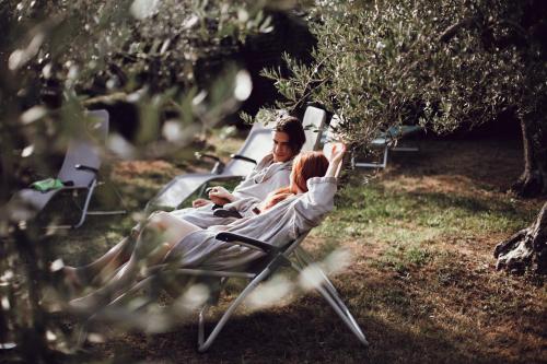 a man and woman sitting in a chair under a tree at Villasanpaolo Resort & Spa in San Gimignano