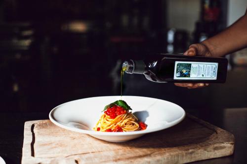 a person pouring sauce on a plate of pasta at Villasanpaolo Resort & Spa in San Gimignano