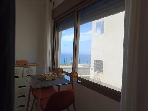 a room with a view of the ocean from a window at Jawhart albahar in Sidi Bouqnadel