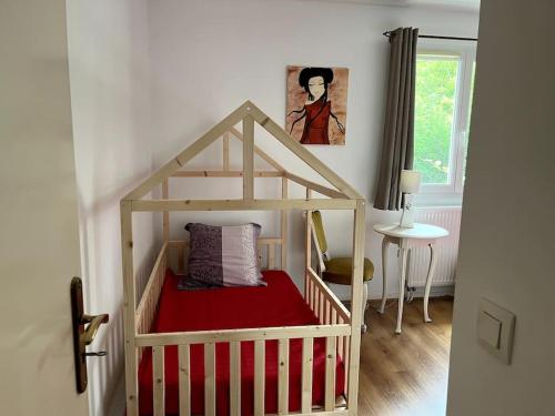 - un lit bébé dans une chambre avec couverture rouge dans l'établissement maison spacieuse, situé au sud de Paris, à Limeil-Brévannes