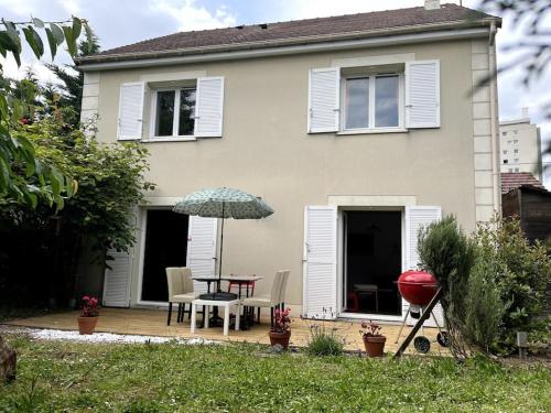 une maison avec un patio avec une table et un parasol dans l'établissement maison spacieuse, situé au sud de Paris, à Limeil-Brévannes