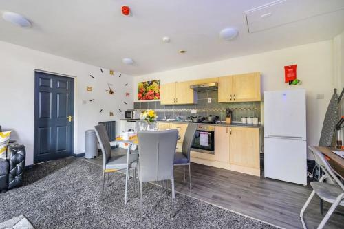 a kitchen with a table and a white refrigerator at -F5GH- For relaxed & Cosy stay, Free Parking, WiFi in Leeds