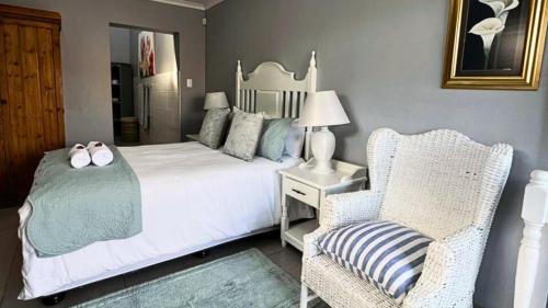 a bedroom with a white bed and a chair at Vasco Diaz Beach in Mossel Bay