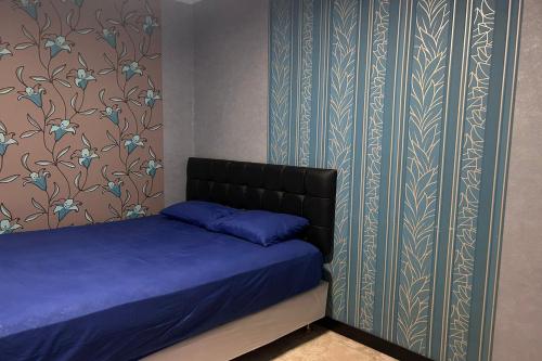 a bedroom with a bed with blue sheets and floral wallpaper at Hotel Kinasih Yogyakarta in Yogyakarta
