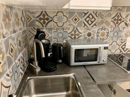 un comptoir de cuisine avec un micro-ondes et un évier dans l'établissement T2 Chic et Cosy à Montréjeau, à Montréjeau