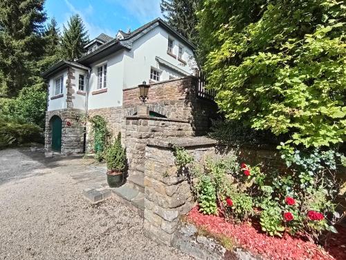 a house with a stone wall and some flowers at Refugium Klosterhaus Nettersheim in Nettersheim