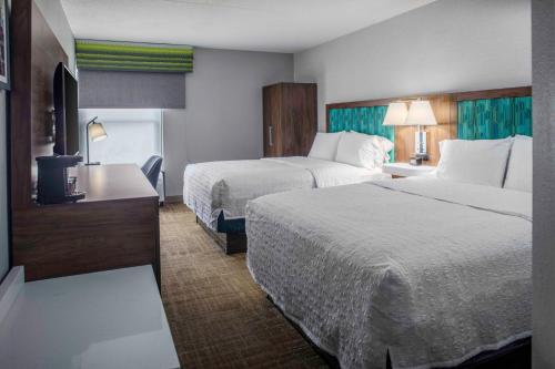 a hotel room with two beds and a desk at Hampton Inn Detroit Northville in Northville