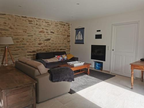 a living room with a couch and a table at Maison de pêcheur restaurée 2022 à 800 m de la plage, GR34 in Moëlan-sur-Mer