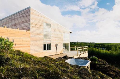 a house on a hill with a tub on a deck at Northern lights Luxury with hot tub! 10 min to city in Mosfellsbær