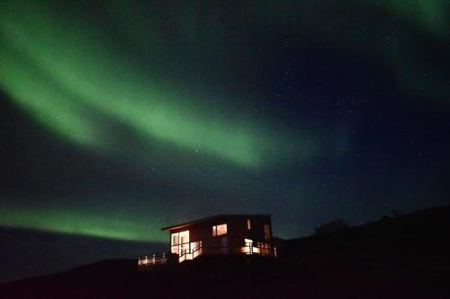 a house under the green northern lights in the sky at Northern lights Luxury with hot tub! 10 min to city in Mosfellsbær