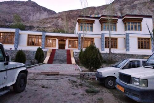 a house with two cars parked in front of it at Kailash Nubra Valley Ladakh by LexStays in Nubra