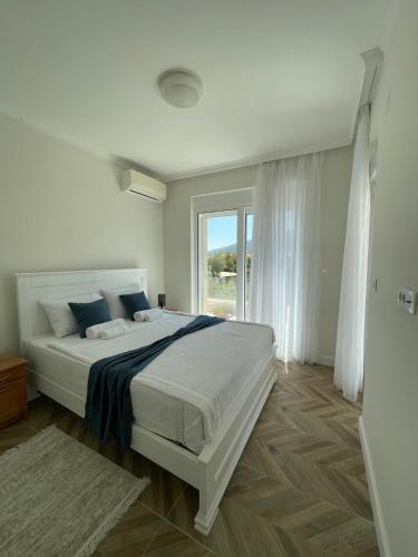 a white bedroom with a large bed and a window at Villa Le Grand Bleu in Đenovići