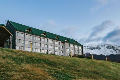 a building on a hill with mountains in the background at Wyndham Garden Ushuaia Hotel del Glaciar in Ushuaia