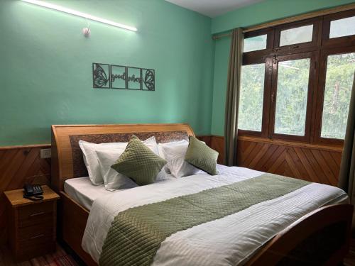 a bedroom with a large bed with green walls at Hotel Geetanjali in Sāngla