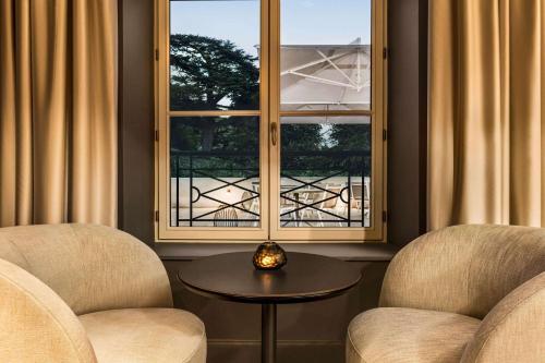 two chairs and a table in front of a window at Dolce by Wyndham Versailles - Domaine du Montcel in Jouy-en-Josas