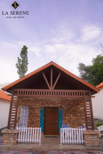 a small brick house with two white chairs in front of it at La Serene Hotel and Resort Kalam by Khan Familia Travels in Kalām