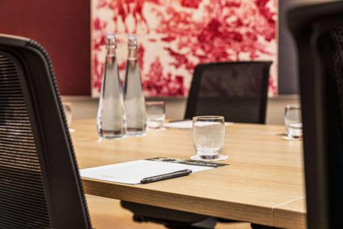 a wooden table with glasses and a pen on it at Dolce by Wyndham Versailles - Domaine du Montcel in Jouy-en-Josas