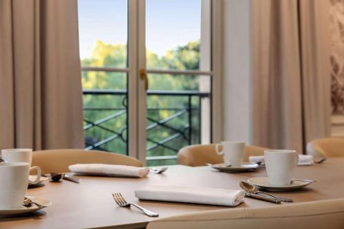a table with plates and utensils and a window at Dolce by Wyndham Versailles - Domaine du Montcel in Jouy-en-Josas