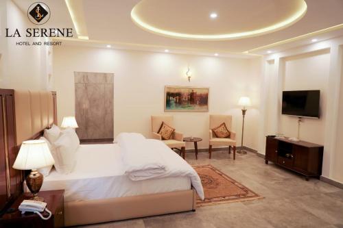 a bedroom with a large white bed and a tv at La Serene Hotel and Resort Kalam by Khan Familia Travels in Kalām