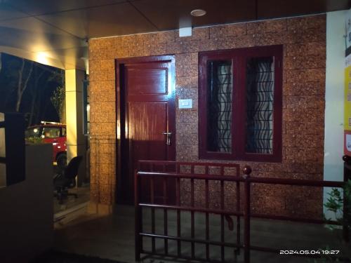 a house with a wooden door and a brick wall at Merlys Fruit Garden in Cochin