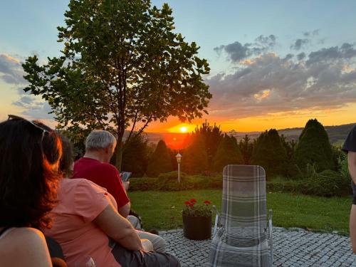 a group of people sitting on a patio watching the sunset at Willa Winnica Maria Anna in Wyżne