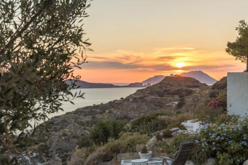 a sunset over the ocean with a table and chairs at Milos Trypiti sunset delux studio in Tripití