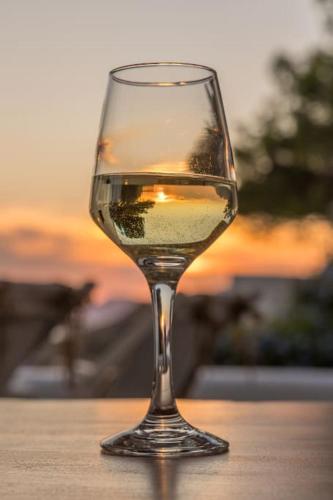a glass of white wine sitting on a table at Milos Trypiti sunset delux studio in Tripití