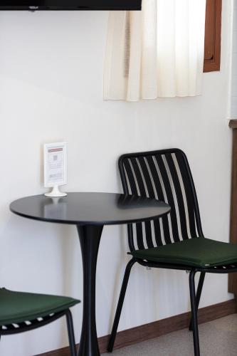 a black table and two green chairs next to a table at Aristea Hotel in Rethymno Town