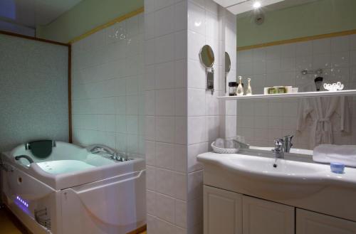 a bathroom with a tub and a sink and a bath tub at Logis Le Midland in Vichy