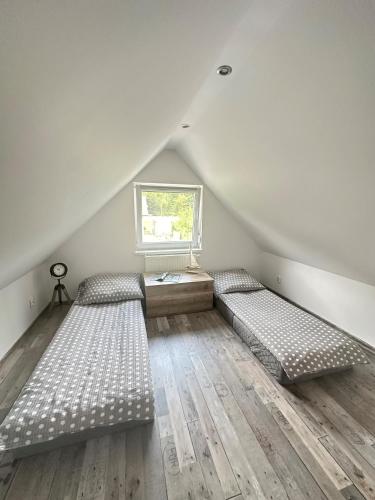 a attic room with two beds and a window at Dom wakacyjny z sauną i ogrodem na wyłączność in Drawno