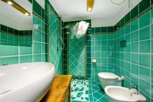 a blue tiled bathroom with a tub and a toilet at Le Chalet du Coq Rouge in Valtournenche