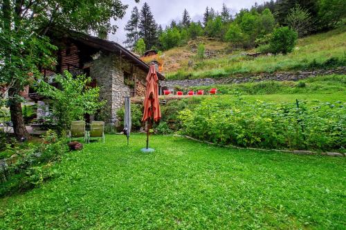 a garden with an umbrella in the grass at Le Chalet du Coq Rouge in Valtournenche