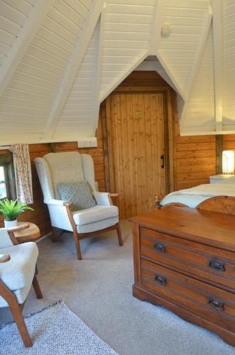 a bedroom with a bed and a chair at Silver Birch Cabin, Bulbury Farm in Lytchett Matravers