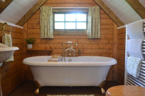 a white tub in a bathroom with a window at Silver Birch Cabin, Bulbury Farm in Lytchett Matravers
