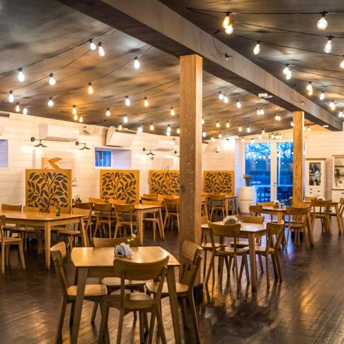 a restaurant with wooden tables and chairs and lights at Pensjonat Sztynort in Sztynort