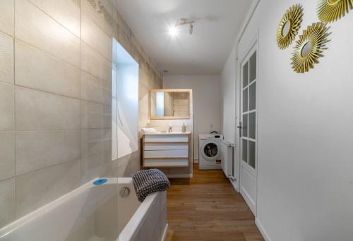 La salle de bains est pourvue d'une baignoire, d'un lavabo et d'un lave-linge. dans l'établissement Le Celestin - Appartement 2 chambres avec jardin en centre ville, à Vichy