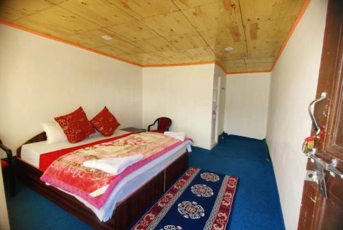 a bedroom with a bed with red pillows on it at Peace Cottages Pangong Ladakh by LexStays in Meruk